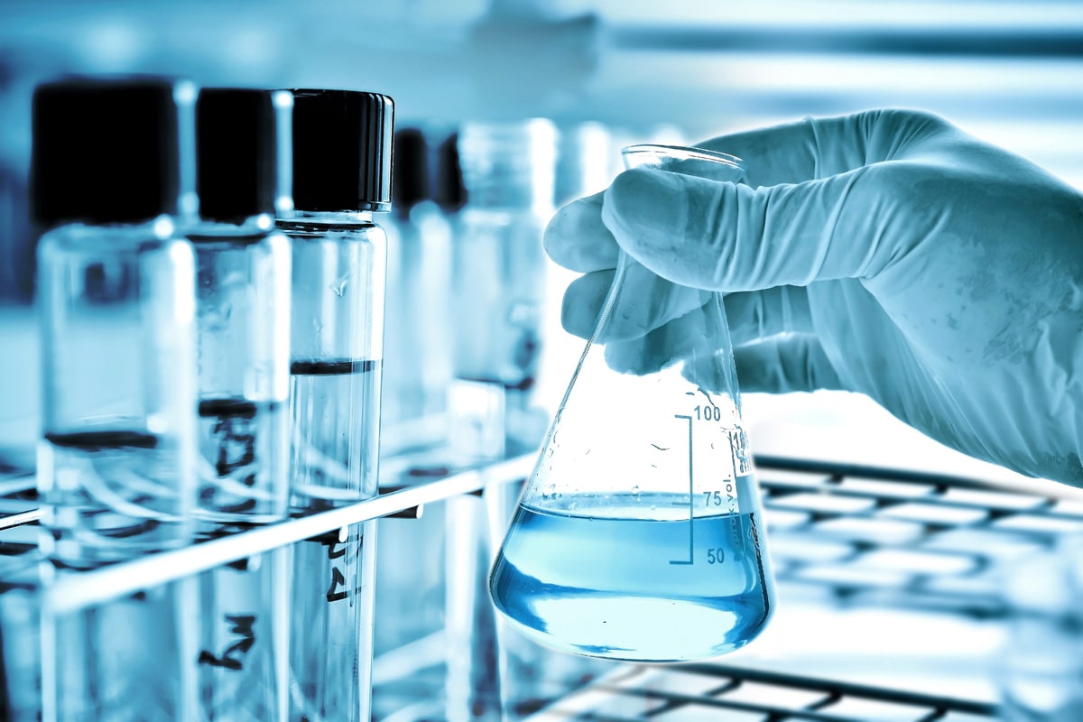 Chemist holding a beaker with blue liquid 
